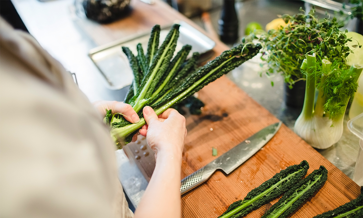 Das Foto zeigt die Hände einer Person, die Gemüse bereitlegt um es zu verarbeiten