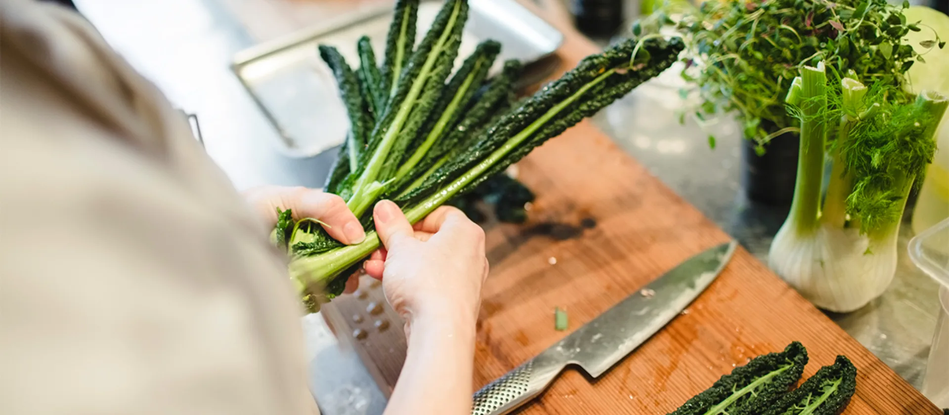 Das Foto zeigt die Hände einer Person, die Gemüse bereitlegt um es zu verarbeiten